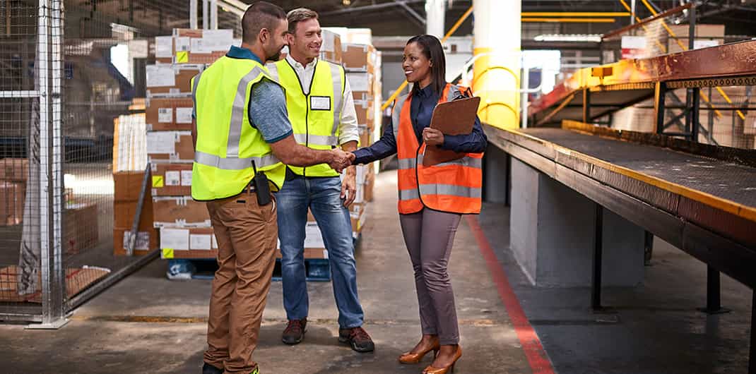 logistics workers shake hands in a distribution warehouse